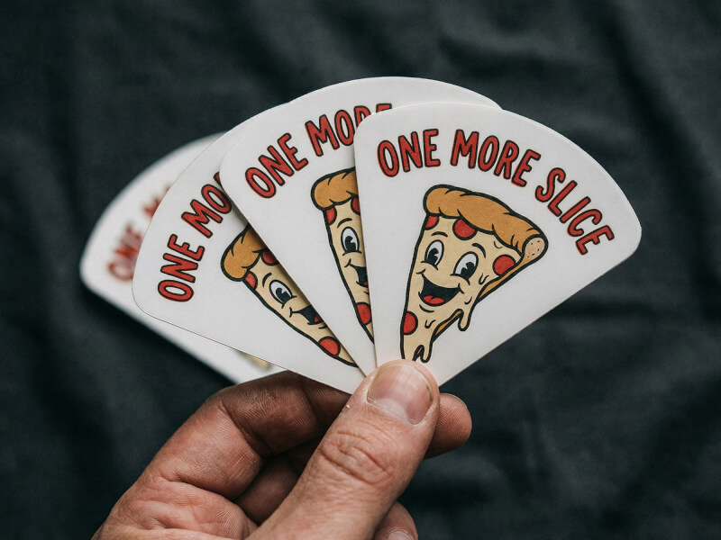 Hand som håller fyra pappersklistermärken uppfläktade som en solfjäder mot mörk bakgrund