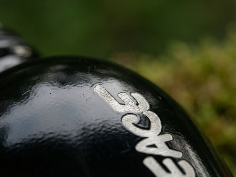 Närbild av silvrigt ingraverad text Greenpeace på en svart glänsande metallflaska