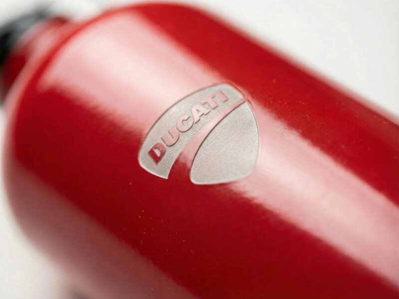 Närbild på en röd vattenflaska Pacific med detaljerad lasergraverad Ducati-logotyp, perfekt som profilprodukt.