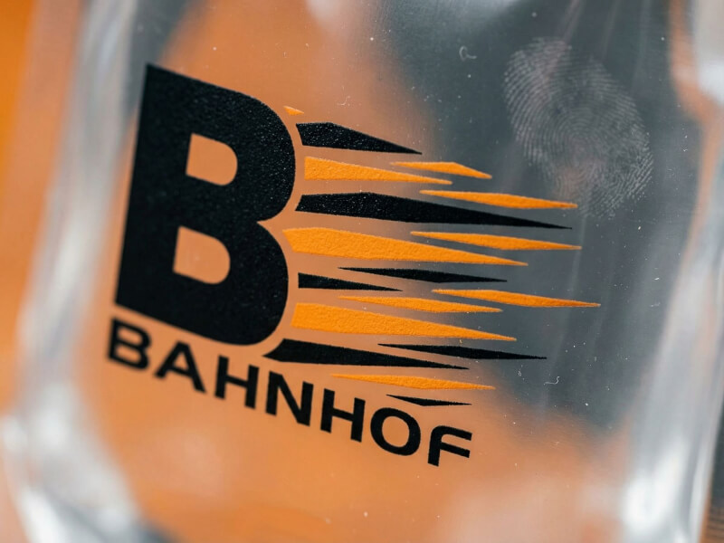 Närbild på tampotryck av Bahnhof-logotyp på transparent Vattenflaska Cabo