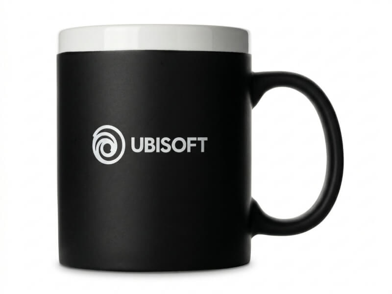 Kaffemugg Chalky med matt svart yta och vit kant upptill, profilerad med Ubisoft-logotyp tryckt på sidan.