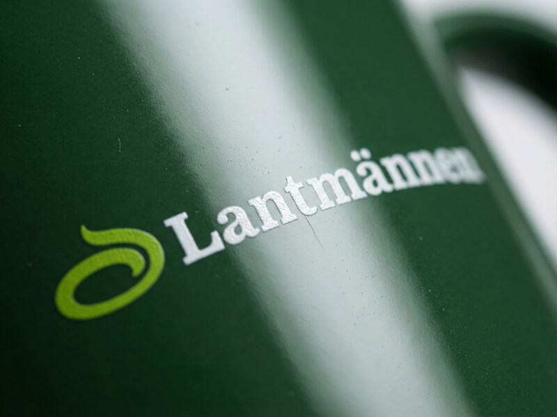 Närbild på en mörkgrön kaffemugg av modellen Santos med Lantmännens logotyp tryckt i vitt och ljusgrönt.