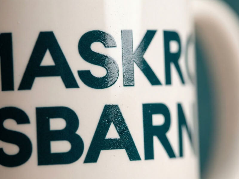 Närbild på en vit glansig keramikkrka med mörkgrön tryckt text skapad genom sublimeringstryck.