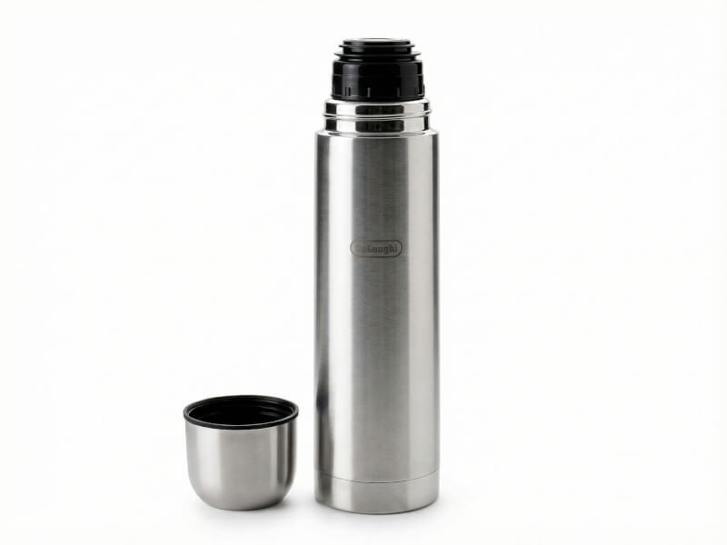 Hög ståltermos med locket avskruvat bredvid sig, utrustad med hällpip, samt DeLonghi-gravyr på vit bakgrund