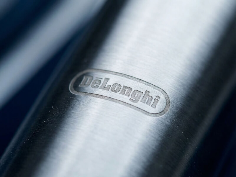 Elegant makrobild av en försiktig DeLonghi-monogramgravyr inbränd på en borstad rostfri ståltermos