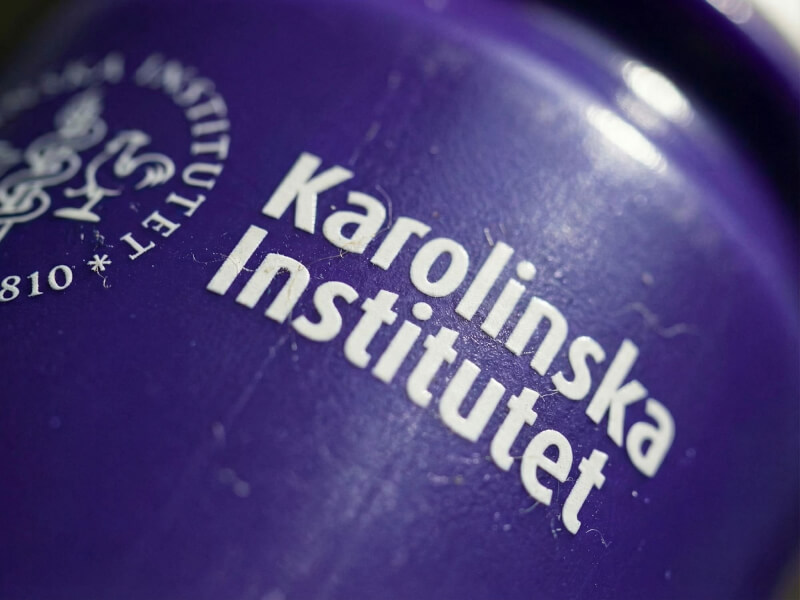 Närbild på den vita cirkulära logotypen och texten Karolinska Institutet tryckt på en glänsande lila sportflaska