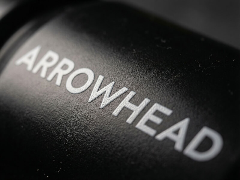 Spännande vinklad närbild av vit Arrowhead Game Studios-logotyp och text mot svart, matt texturerad bakgrund