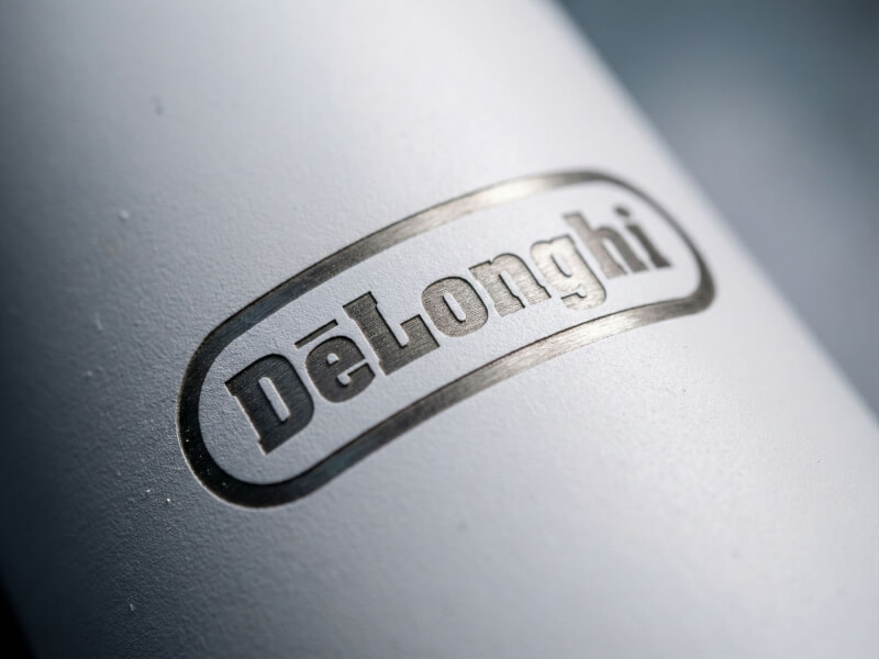 Närbild på en matt vit Termosflaska Thor 650 med lasergravyr av DeLonghi-logotypen, som visar rostfritt stål under beläggningen.