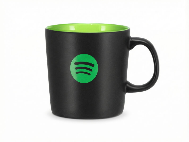 Stengodsmugg Emma Svart med matt finish, grön insida och tryckt Spotify-logotyp på vit bakgrund.