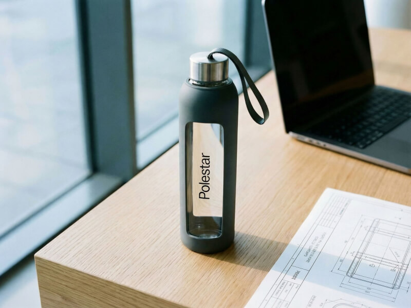Tampotryckt vattenflaska tide i aluminium med skruvlock fotograferad i bilverkstad med Polestar-bil
