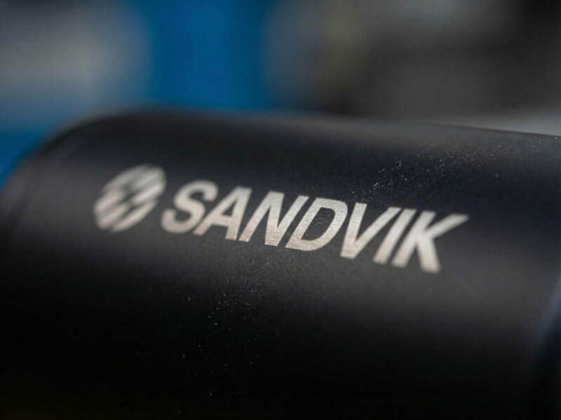 Närbild med mjuk fokusering på ljusgrå och silverblänkande Sandvik-logotyp lasergraverad på en matt svart termos