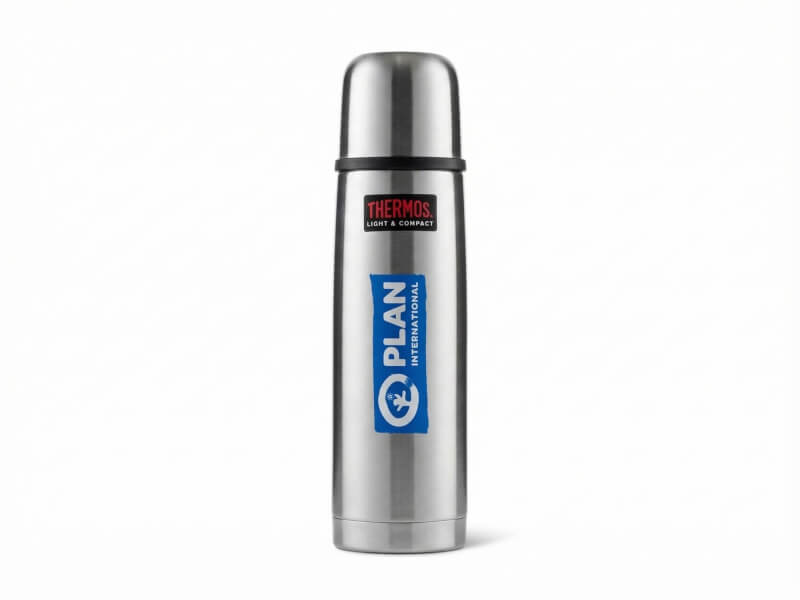 Borstad ståltermos från varumärket Thermos med klassisk stålkopp samt vertikal blå logotyp för Plan International på vit bakgrund