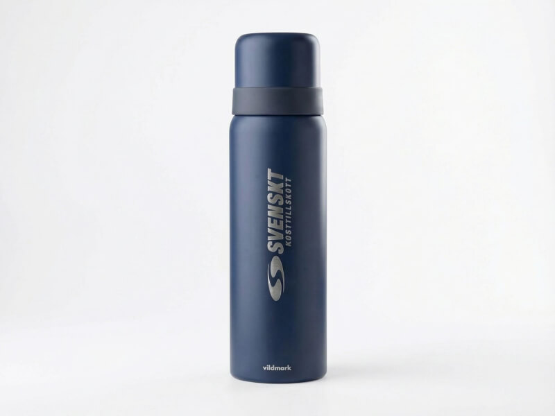Mörkblå slimmad termos med silverfärgat lock, vit och silverfärgad Svenskt Kosttillskott logotyp på vit bakgrund