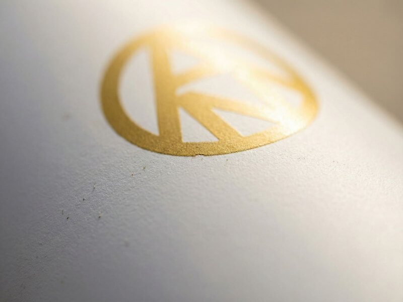 Snygg och ljus närbild av ett lyxigt guldtryck med Arvid Nordquist logotyp centrerad på en vit termos