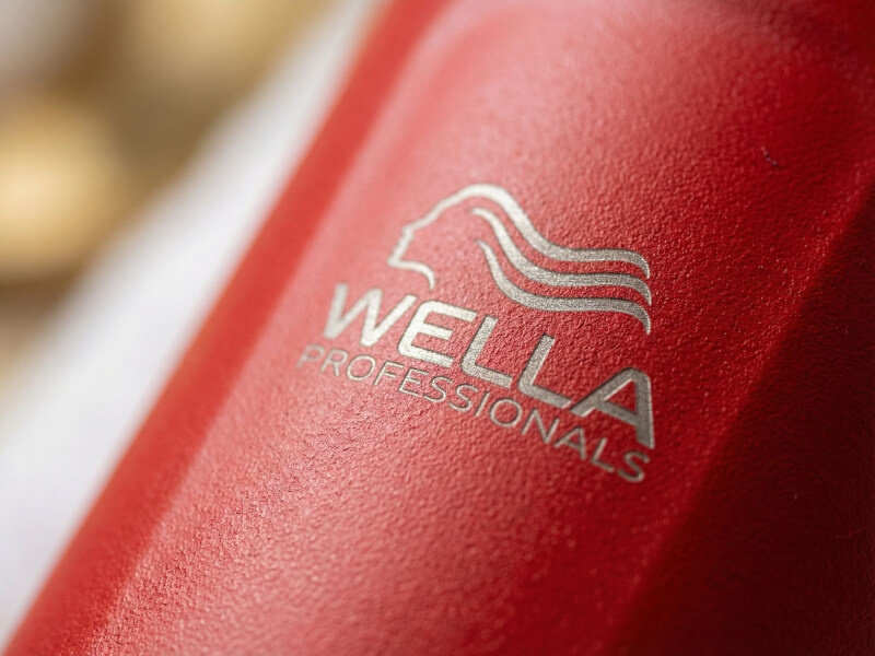 Närbild på en röd termosmugg Thor 350 med texturerad matt yta och en elegant laser-graverad Wella Professionals-logotyp.