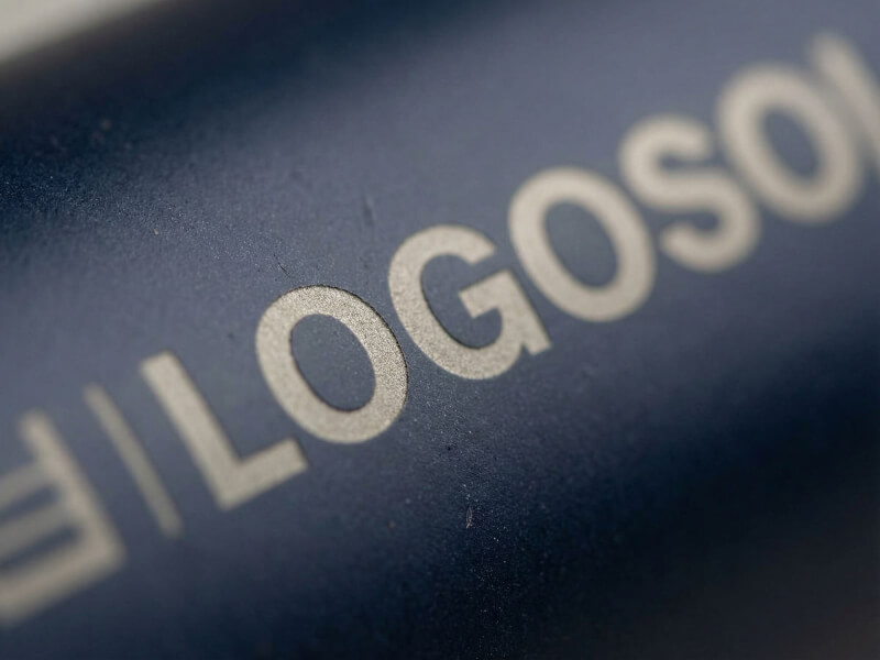 Närbild av en marinblå termosmugg Metro med laser-graverad logotyp på en matt, lätt texturerad yta.