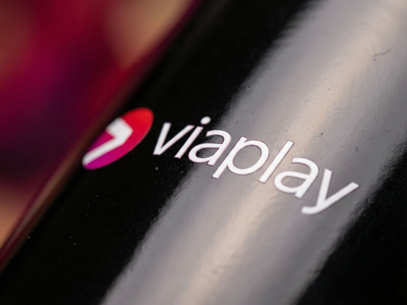 Närbild av en blank svart stengodsmugg Emma med tryckt vit och röd Viaplay-logotyp.