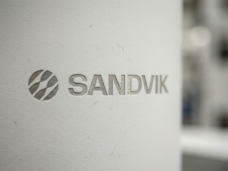 Närbild av en matt vit termosmugg Can 330 med Sandviks logotyp lasergraverad i metallen.