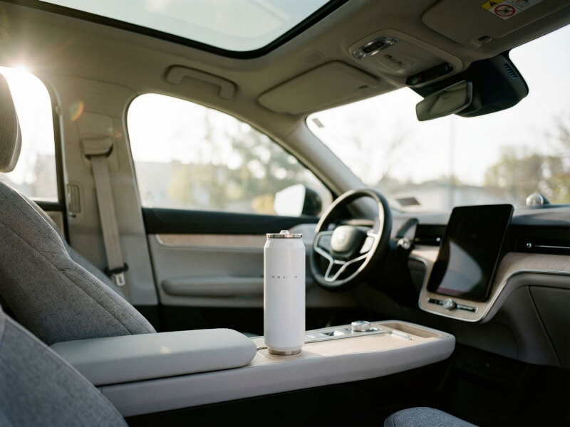 Vit Volvo-burktermos placerad i mittkonsolen på en modern bilinteriör i behagligt dagsljus