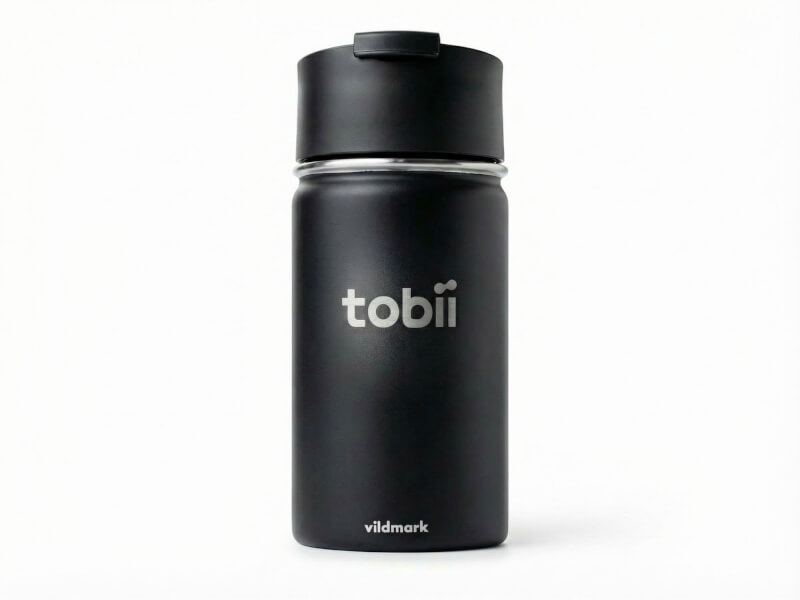 Svart matt termosmugg Canister med laser-graverad Tobii-logotyp, isolerad flaska mot vit bakgrund.