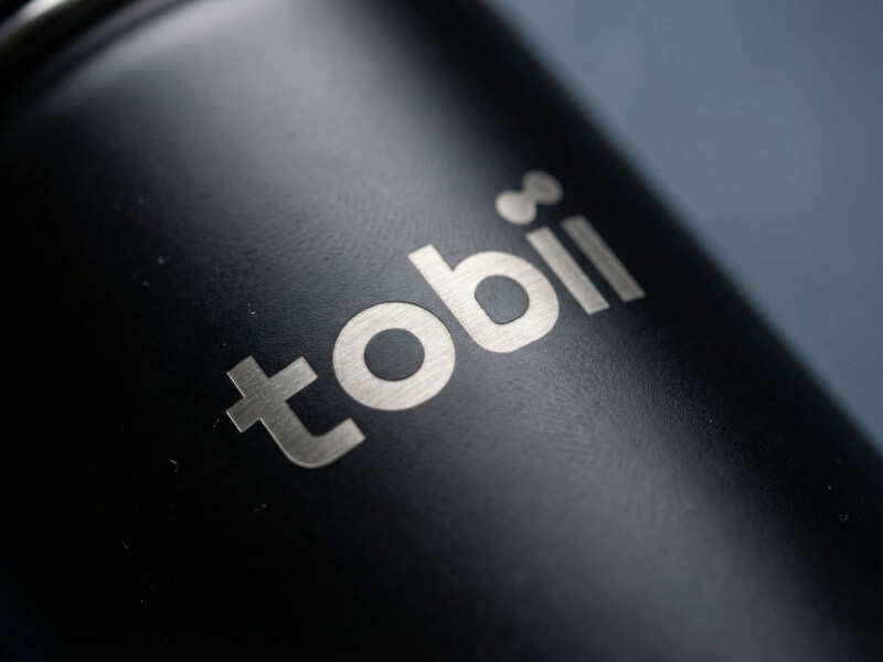 Närbild på en matt svart termosmugg Canister med Tobii-logotyp utförd med precisionslasergravyr.