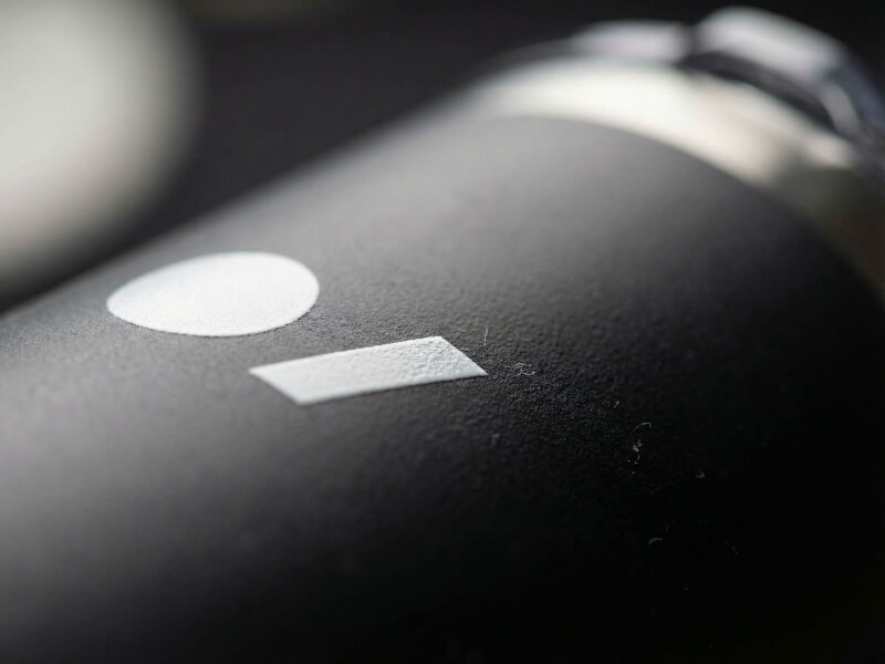 Närbild på en matt svart termosmugg Pika med vit tryckt logotyp och strukturerad yta.