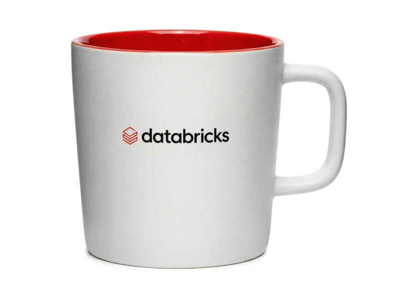 Vit stengodsmugg Ebba med matt finish, röd insida och tryckt Databricks-logotyp, isolerad mot vit bakgrund.