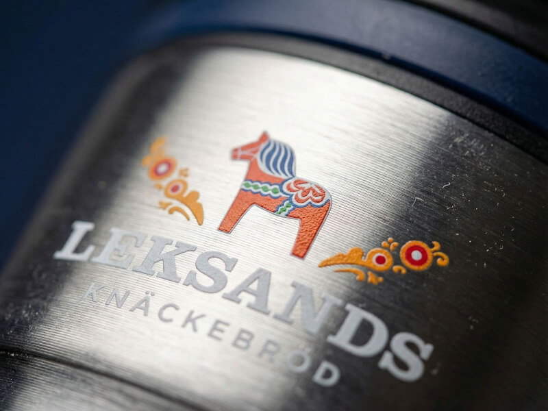 Närbild på Termosmugg Bayamo i borstat rostfritt stål med ett färgglatt tryck av en dalahäst och Leksands Knäckebröds logotyp.