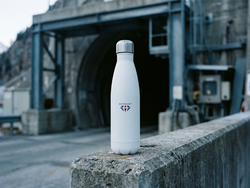 Den vita termosen från Bergteamet stolt stående på ett betongfundament invid en stor uthuggningstunnel eller industriell passage