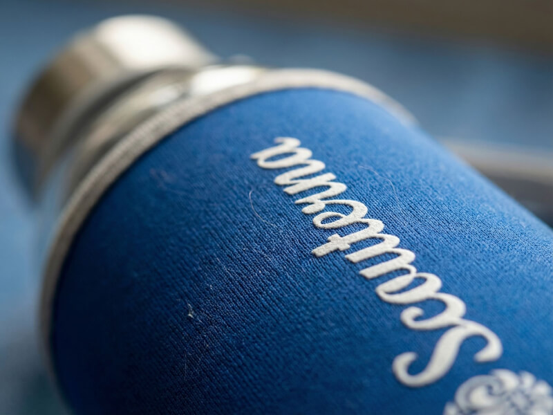 Närbild på texten Scouterna tryckt i vitt på ett blått tygöverdrag till en vattenflaska