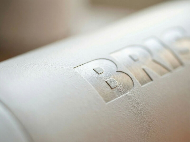 Närbild på en matt vit Termosflaska Vasa Återvunnen i studiomiljö, som visar detaljerad lasergravyr där det underliggande rostfria stålet träder fram.