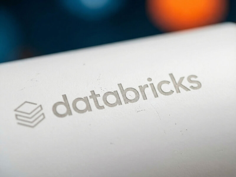 Närbild på en vit termosmugg av modellen Melbourne med en laser-graverad Databricks-logotyp, fotograferad i en professionell kontorsmiljö.