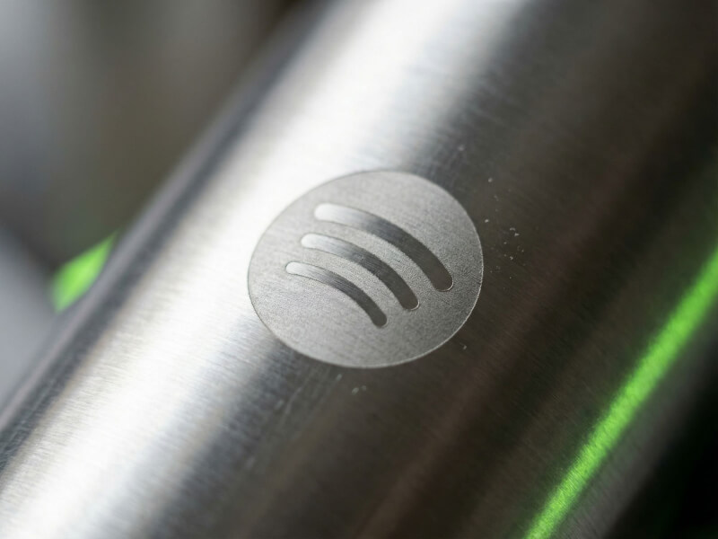 Närfotograferad, subtil men knivskarp lasergravyr av Spotifys cirkulära logotyp på den snygga borstade metallytan